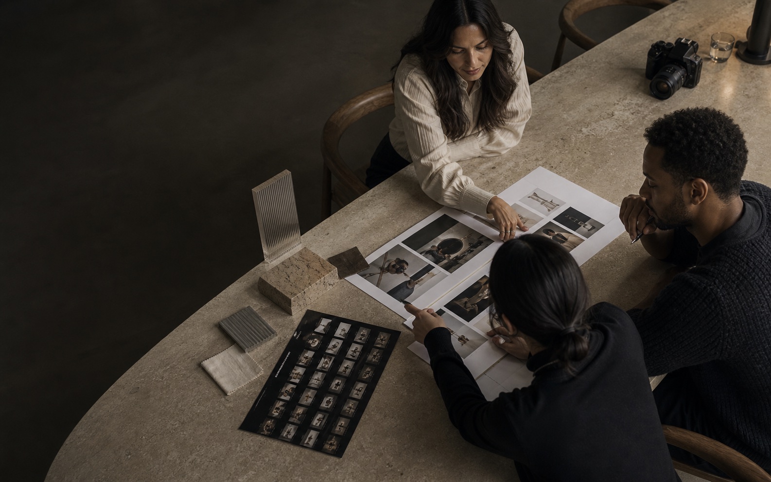Brand strategist and creators reviewing campaign frames around a stone table